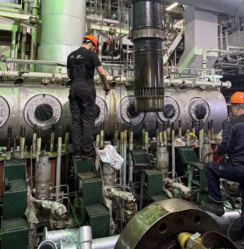 Engine room technicians inspecting large machinery on a vessel.