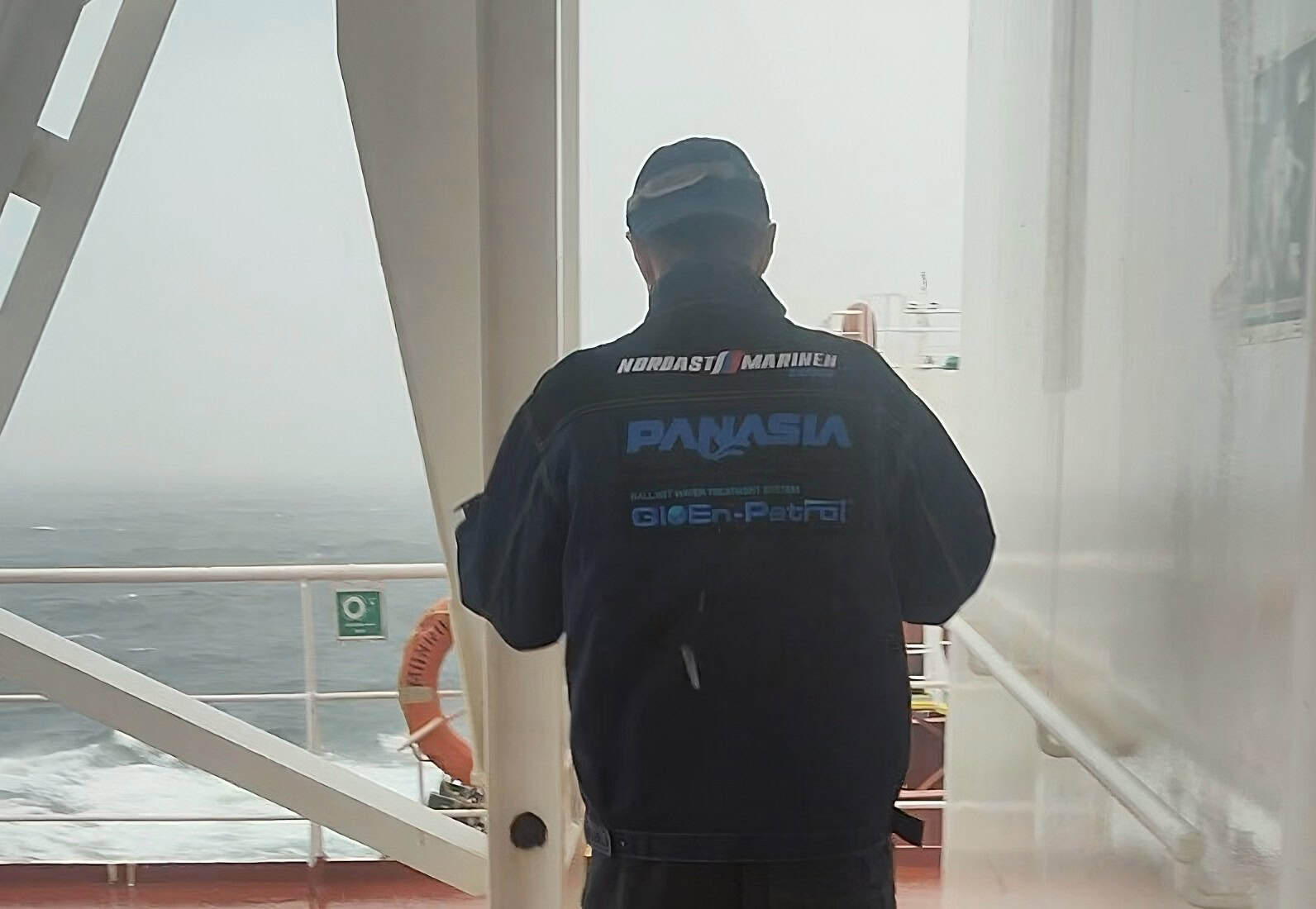 Nordast engineer in marine gear on ship deck with ocean view.