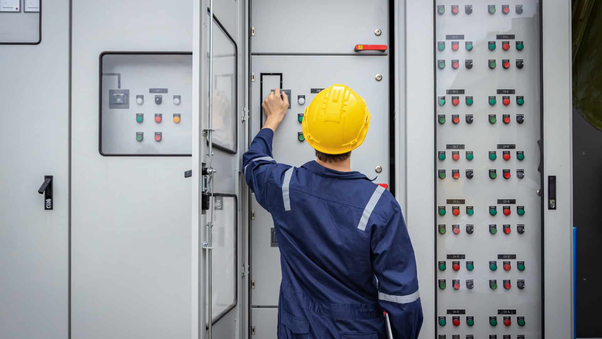 Nordast engineer in safety gear inspecting electrical control panel.