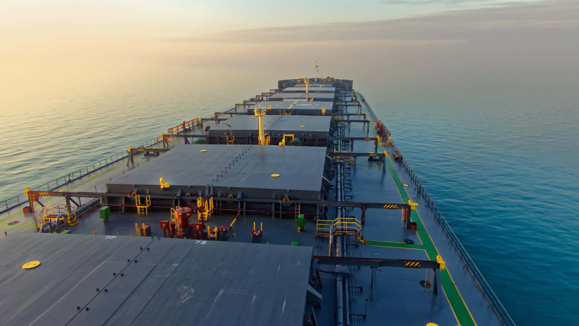 View of a ship's deck with various equipment and pipelines at sea.