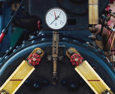 Close-up of marine engine with pressure gauge and valves.