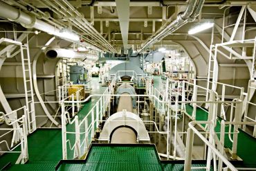 View of a ship engine room with pipes and machinery.
